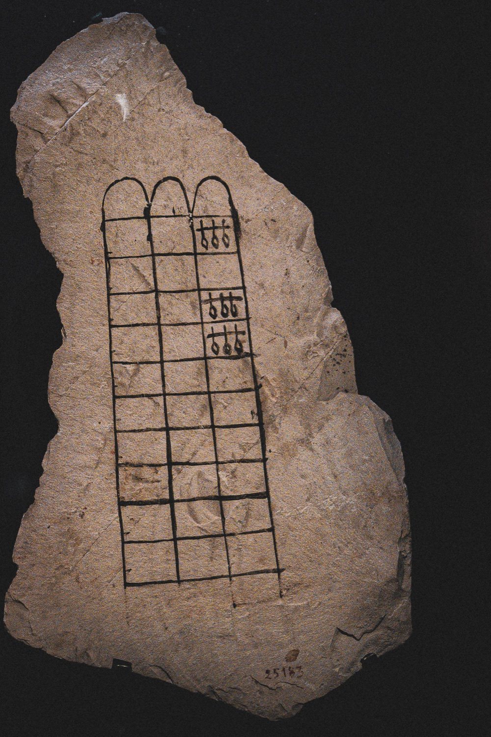 A limestone ostracon incised in ink with a senet board — the full shard, catalogue number 25183, lit against black.